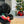 Load image into Gallery viewer, P.L.A.Y. Home for the Holidays Collection Holiday Hauler - toy being played with by black Poodle on woven rug in front of fireplace and Christmas Tree
